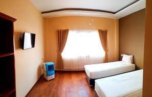 Ein Hotelzimmer mit Bett, Fernseher, Heizung und einem fenster mit Vorhängen.