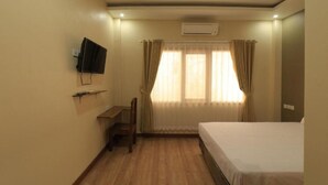 A hotel room with a bed, a desk, and a television mounted on the wall. - Bluefire Homestay Syariah (Banyuwangi)