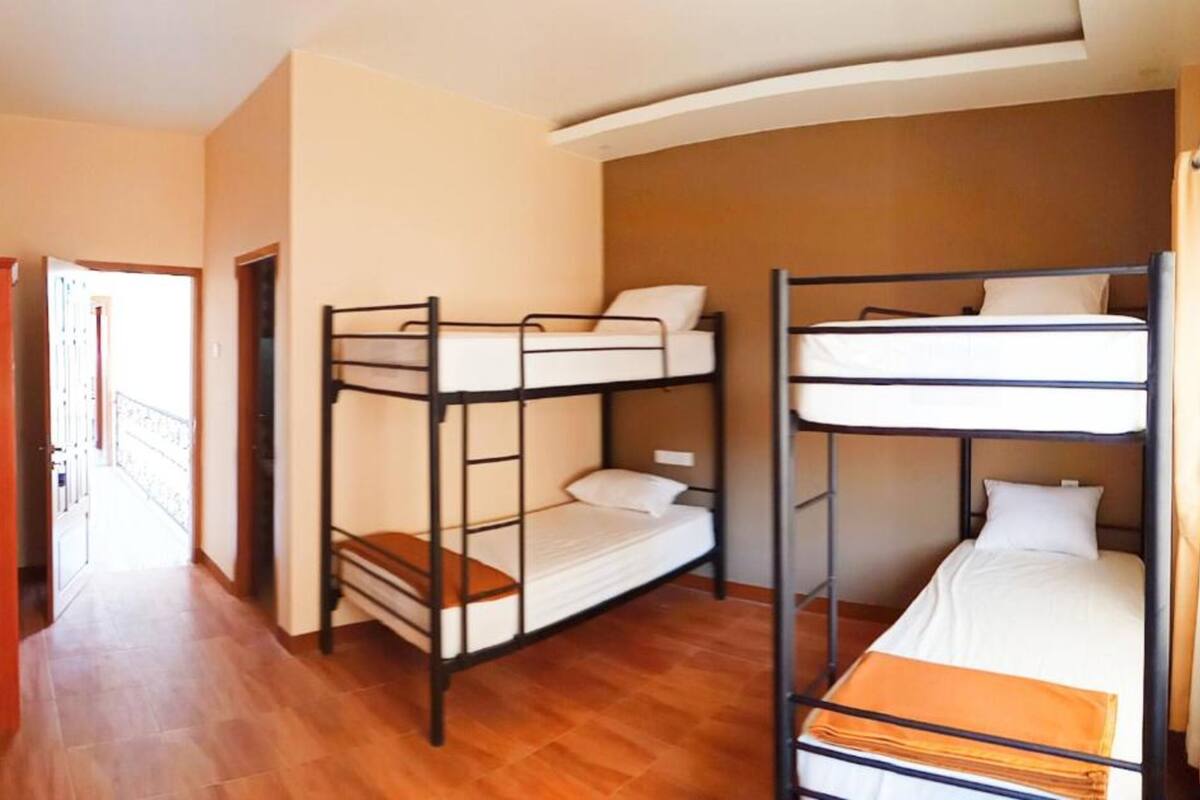 Una camera del dormitorio con letti a castello, pavimento in legno e una porta che dà su un corridoio.