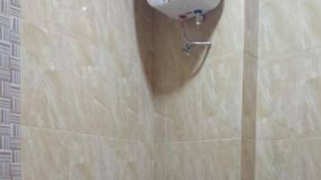 A bathroom with a toilet, a hand dryer, and a wall-mounted soap dispenser.