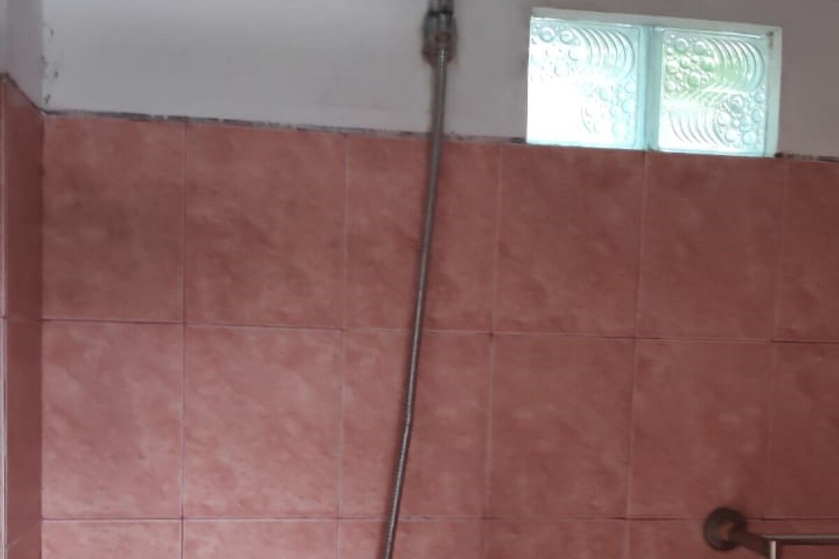 A shower with a handheld hose and a wall-mounted showerhead.