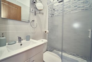 A modern bathroom with a white sink, mirror, and toilet.