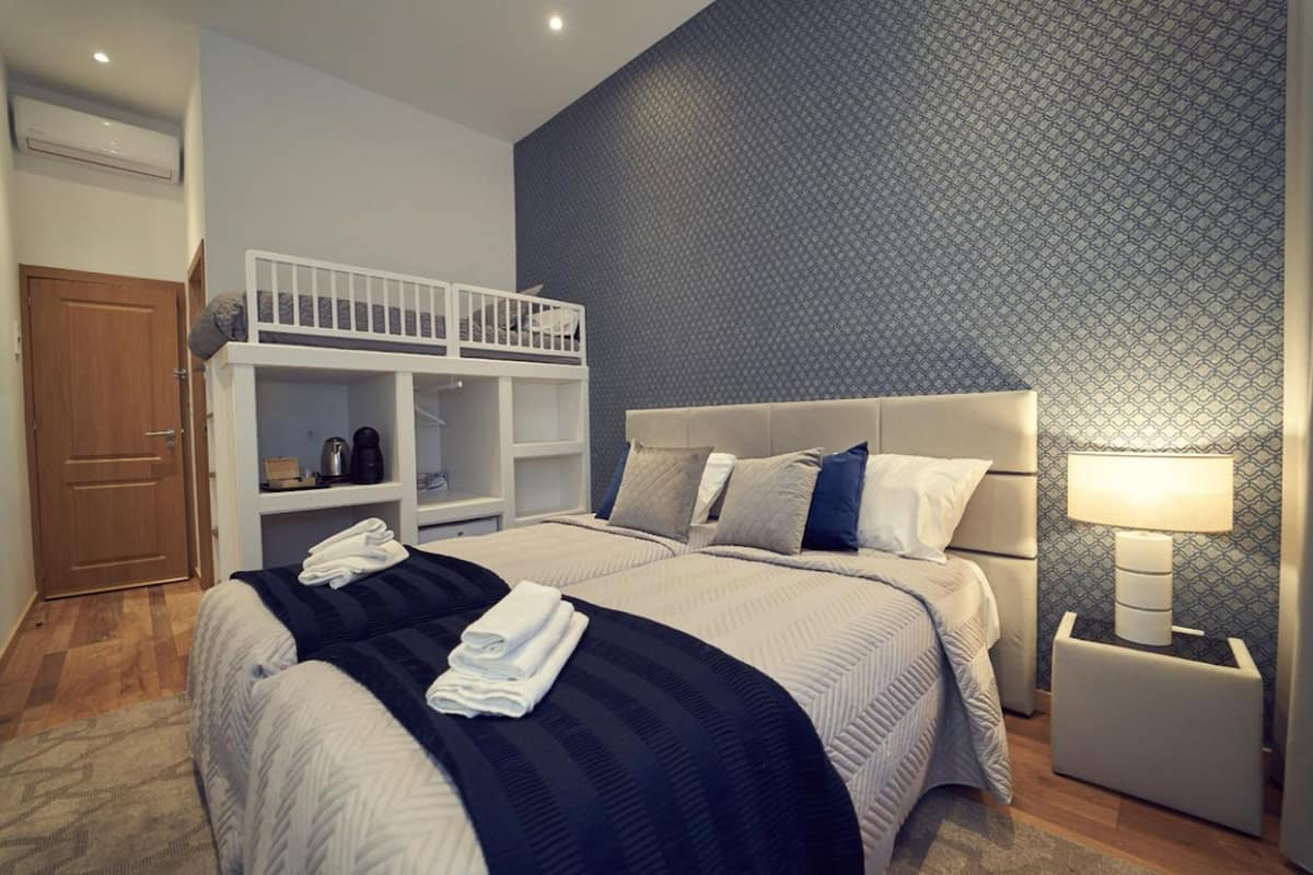 Ein Hotelzimmer mit Etagenbett, einem Einzelbett, einem Nachttisch mit Lampe und einem Kleiderschrank.