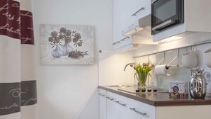 Una cucina moderna con mobili bianchi, un forno a microonde, un lavello e un vaso decorativo con fiori.