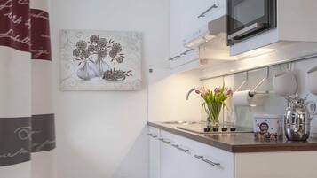 Eine moderne Küche mit weißen Schränken, einer Mikrowelle, einem Spülbecken und einer dekorativen Vase mit Blumen.