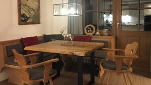Zona pranzo con tavolo e sedie in legno, un lampadario e un quadro appeso al muro.