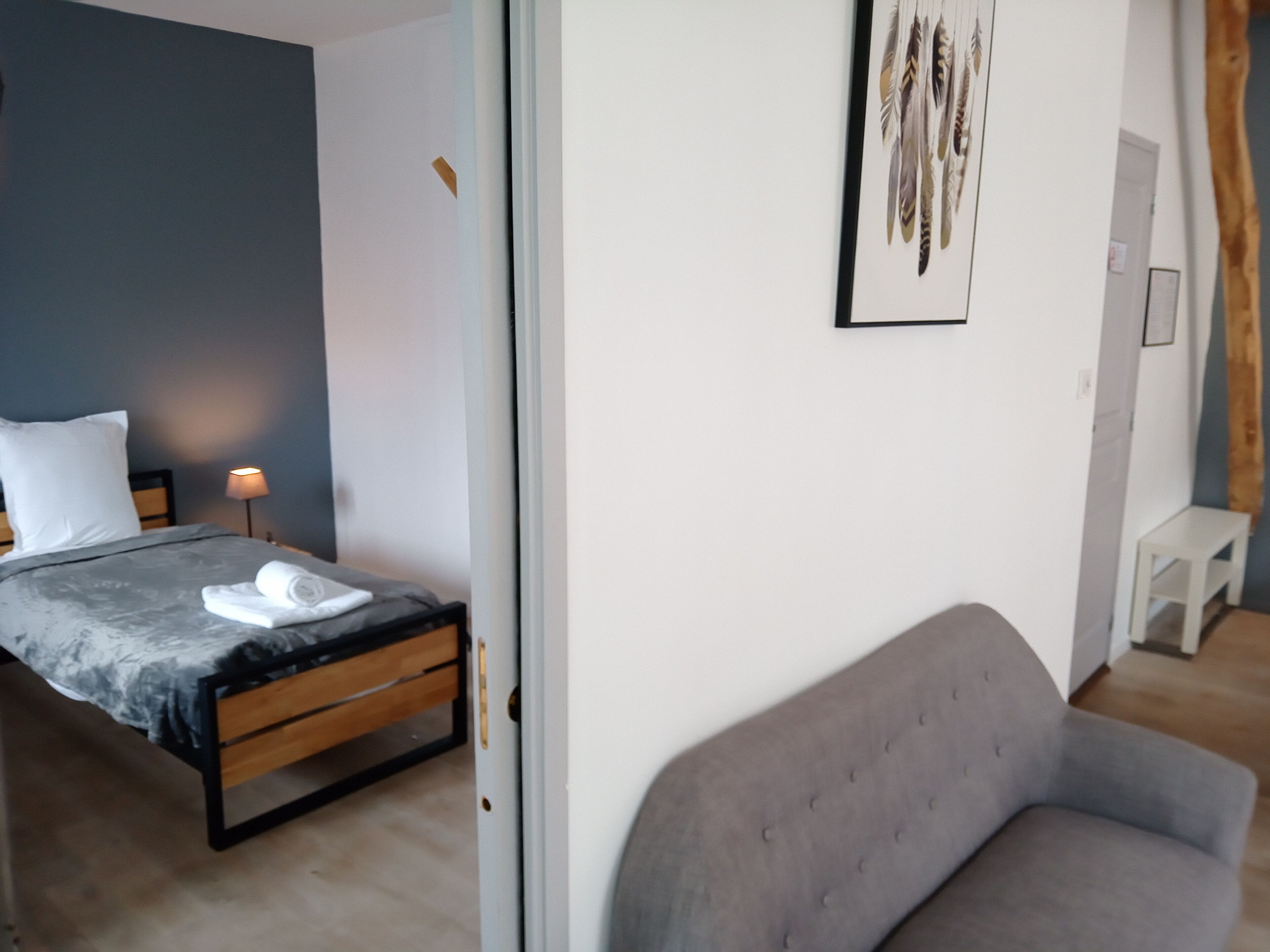 Une chambre à coucher moderne avec un lit, une table de chevet et un canapé gris.
