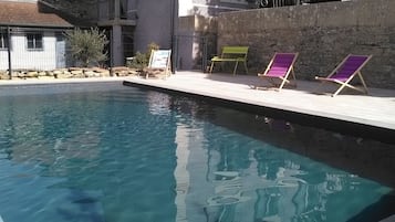 Una piscina al aire libre de temporada, sombrillas