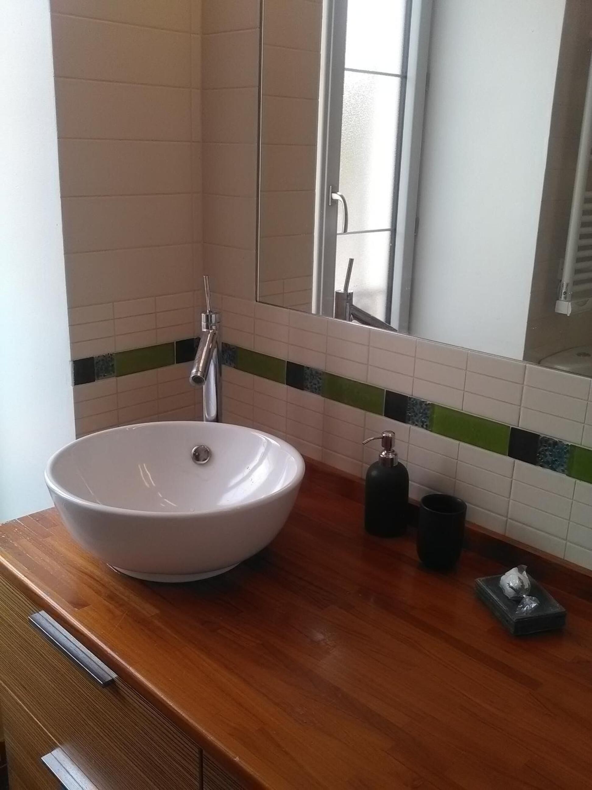 Ein Badezimmer mit einem weißen Aufsatzbecken, einem Spiegel und einer Holzausstattung.