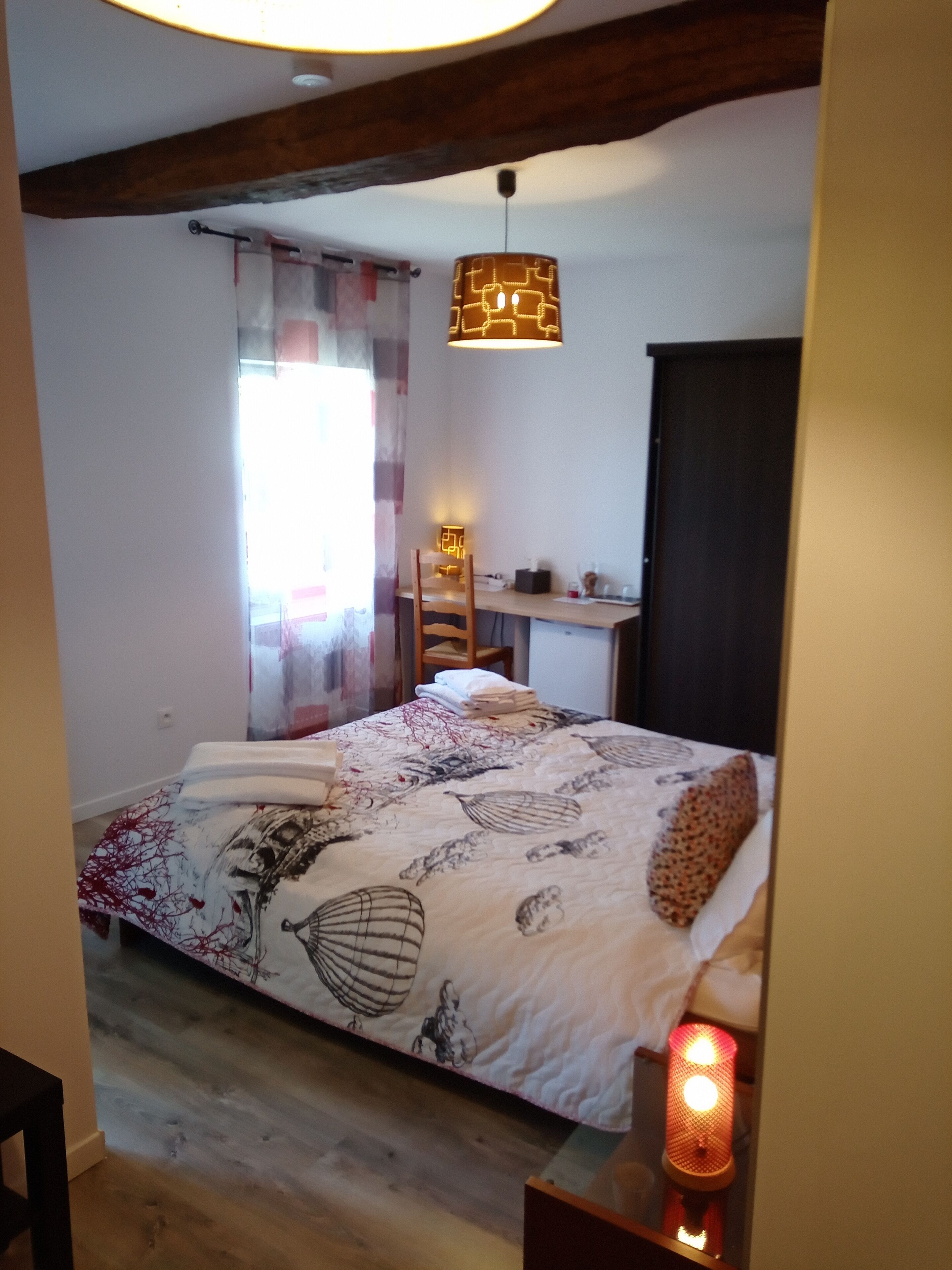 Un dormitorio con cama, escritorio y lámpara colgante.