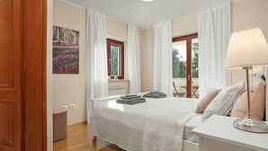 A bedroom with a bed, a desk, a lamp, and a window with curtains.