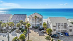 A beachfront hotel with multiple-story buildings, a parking area, and a view of the ocean. - "Leeward I-7" | Beachfront Condo with Stunning Views of the Water | Bike to Seaside (Seagrove Beach)