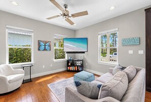 A living room with a ceiling fan, a flat-screen TV, a bookshelf, and a couch.