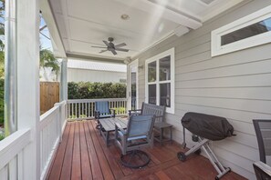 A covered porch with a ceiling fan, a table and chairs, and a grill.