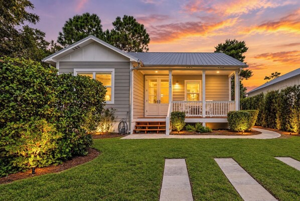 A single-story house with a porch, a well-maintained lawn, and a clear sky.