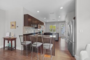 A modern kitchen with a central island, bar stools, and stainless steel appliances.