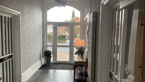 A hallway with a wooden floor, a white door, and a view of the street outside. - Claremont Hotel (Preston)