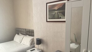 A hotel room with a bed, a bedside table with a lamp, a chair, and a wardrobe. - Claremont Hotel (Preston)