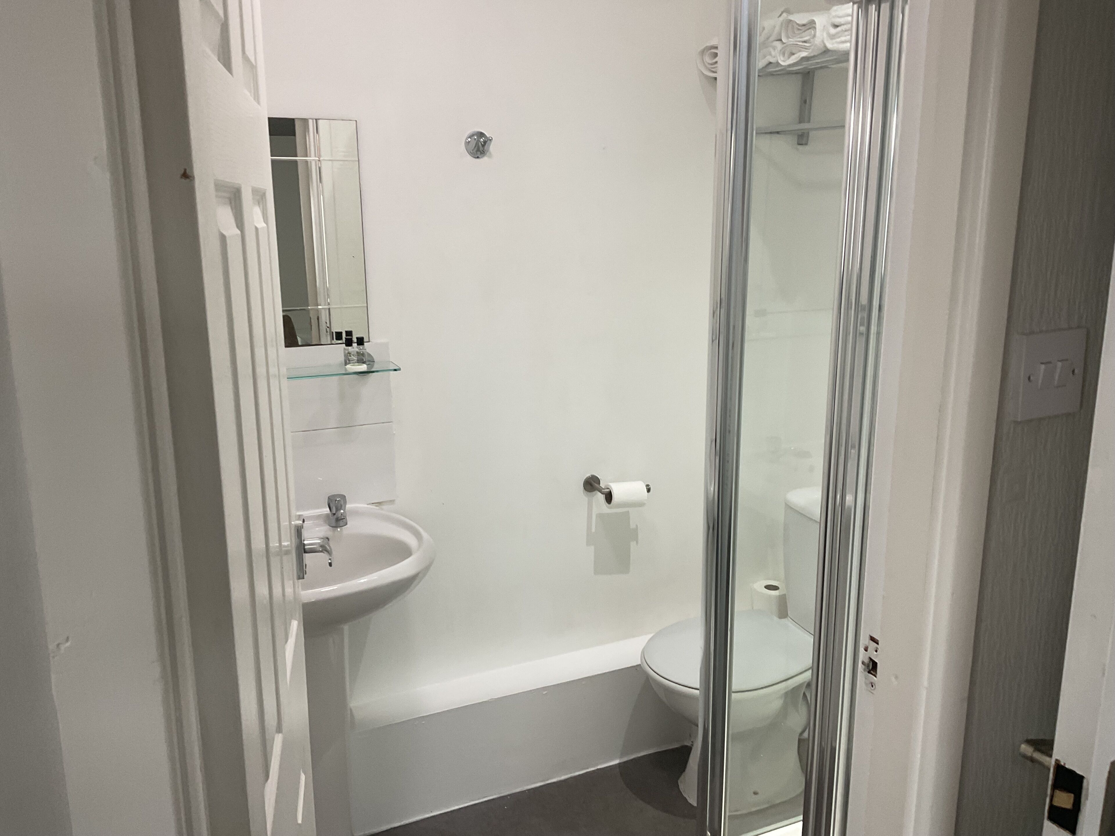 Une salle de bain avec une douche à parois de verre, un lavabo blanc et des toilettes.