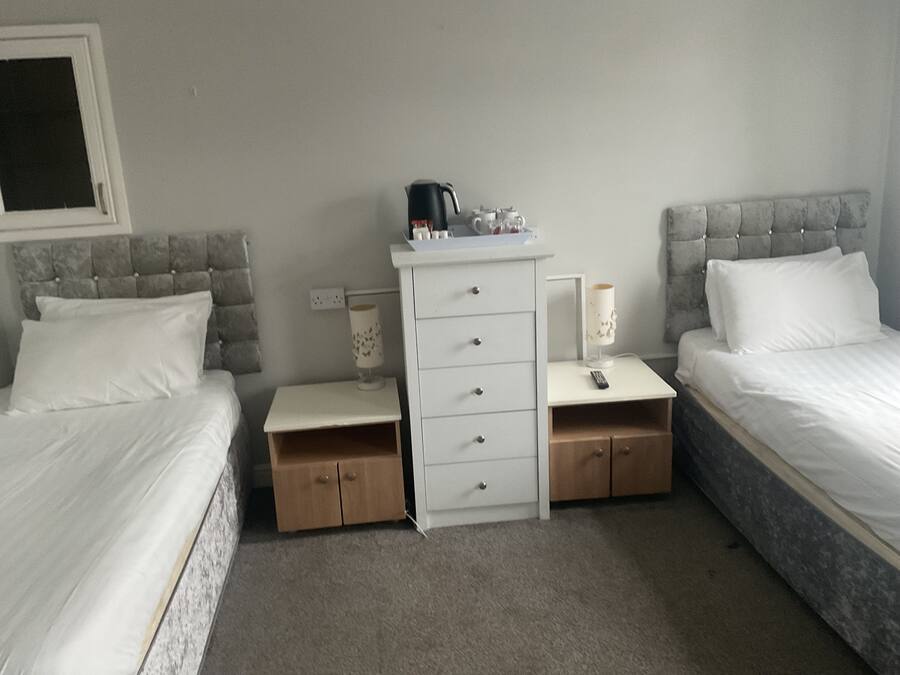 Habitació d'hotel amb dos llits, un tocador blanc, una petita taula de nit i una làmpada.