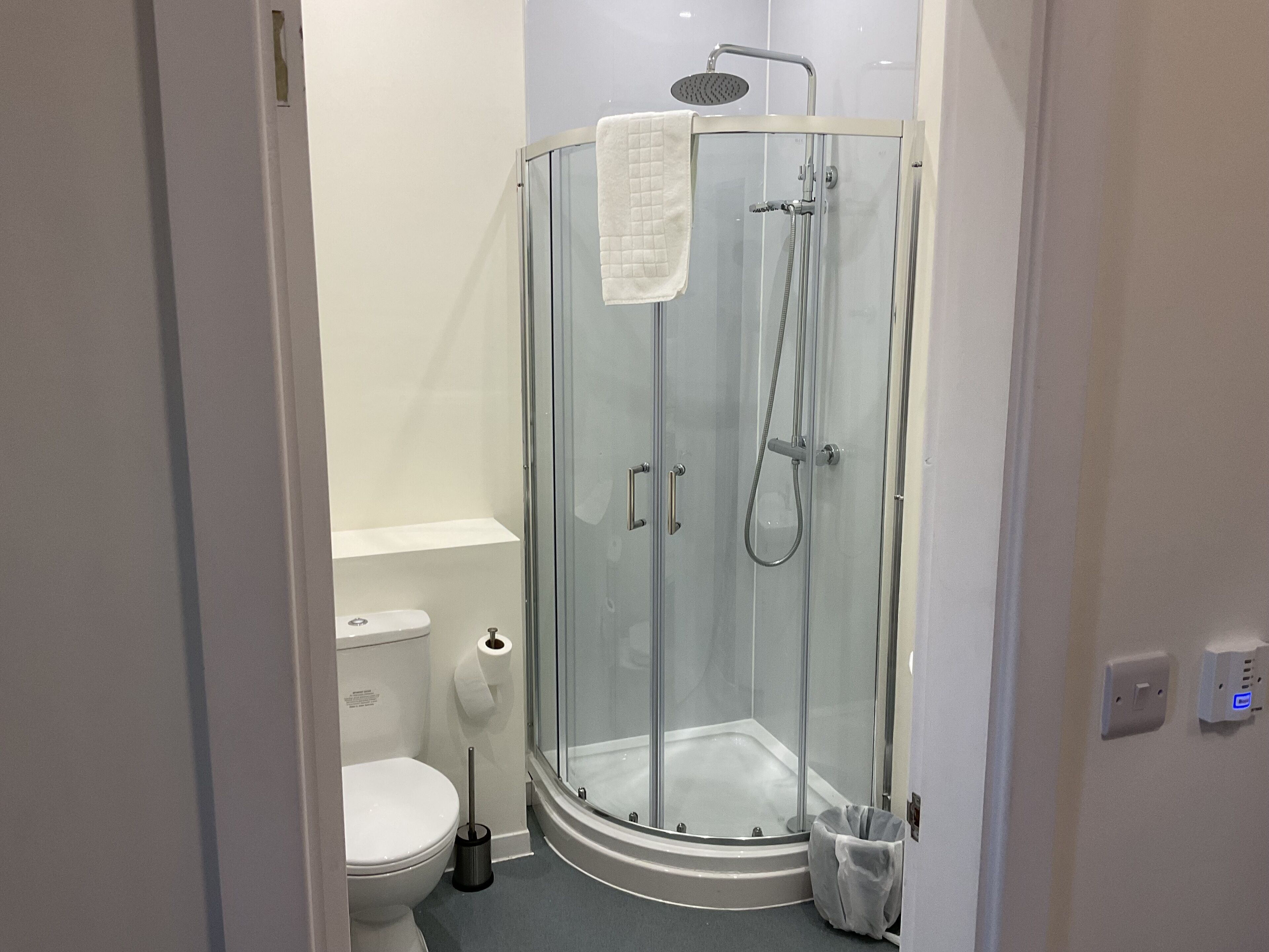 A modern bathroom with a glass-enclosed shower, a toilet, and a bidet.