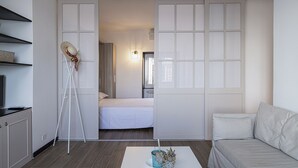 A modern bedroom with a bed, a white wardrobe, a white sofa, and a small plant on a white table. - Sapore di Sale by Wonderful Italy (Genoa)