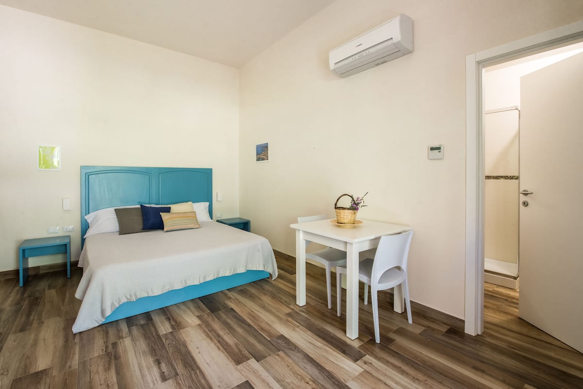 A bedroom with a bed, bedside table, and a small table with a chair.