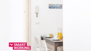 A modern dining area with a table set for two, a white telephone, and a wall-mounted light switch.