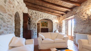 A rustic interior with stone walls, wooden beams, and a white sofa set. - Relax at the Swimming Pool by Wonderful Italy (Cefalù)