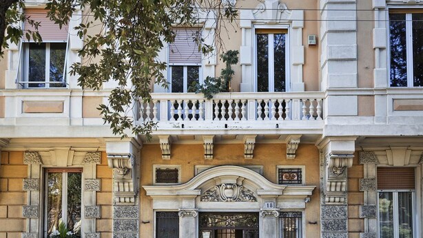 A building with a classical facade, a balcony with balustrades, and a large arched entrance. - Cozy Family Apartment in Castelletto by Wonderful Italy (Genoa)