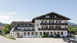 A traditional European hotel with a prominent sign, multiple balconies with flower boxes, and a parking lot in front. - Ferienwohnung (Marquartstein)