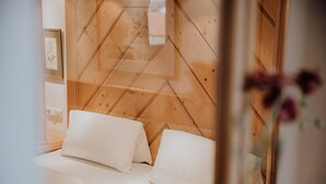 A bedroom with a wooden headboard, two white pillows, and a bedside table. - Ferienwohnung (Marquartstein)