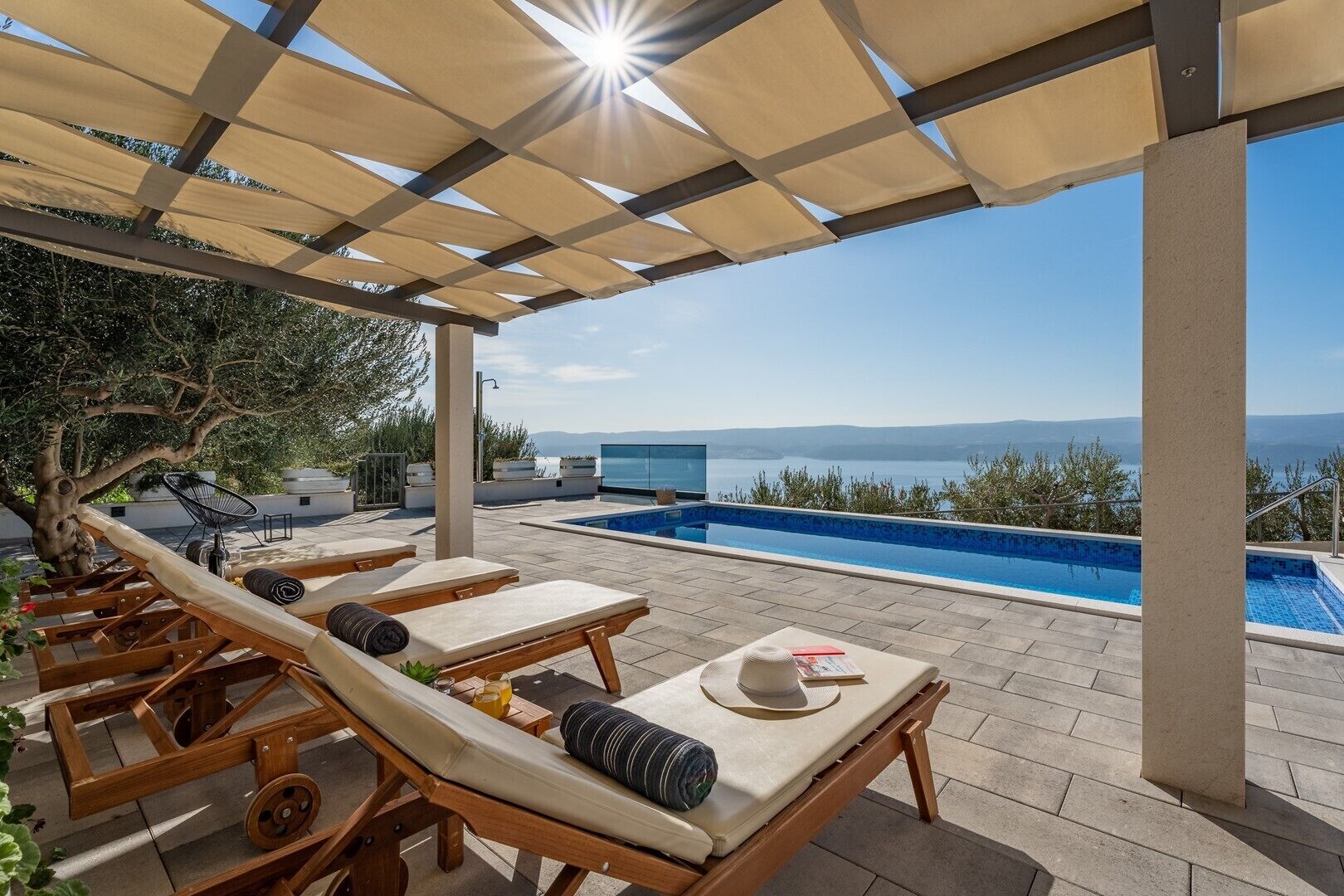 Ein Poolbereich auf dem Dach mit Liegestühlen und Blick auf das Meer.