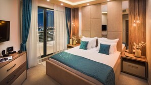 Una habitación de hotel moderna con una cama grande, un escritorio con televisión de pantalla plana y un balcón con vista a la ciudad.