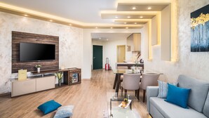 Una sala de estar moderna con un televisor de pantalla plana, un sofá, una mesa de centro y un comedor con sillas.