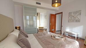 A bedroom with a large bed, a bedside table with a lamp, a wooden door, and a wall with abstract art. - Wonderful  villa for 6 people with WIFI, TV, terrace and panoramic view, close to Forte Dei Marmi (Marina Dei Ronchi)