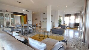 A spacious living area with a large sofa set, a dining table with chairs, a small coffee table, and a TV in the background. - Wonderful  villa for 6 people with WIFI, TV, terrace and panoramic view, close to Forte Dei Marmi (Marina Dei Ronchi)