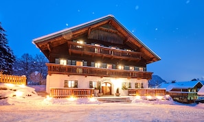 A multi-story chalet with a wooden facade, balconies, and a snow-covered entrance. - Gut Vögeihof (Forstau)