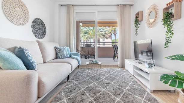 A modern living room with a sofa, TV, and decorative wall pieces. - Syros Apartment (Javea / Xàbia)