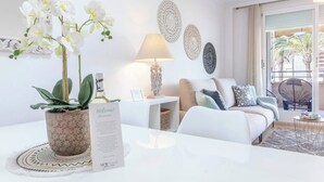 A modern living room with a white sofa, a coffee table, and decorative items including orchids and wall art. - Syros Apartment (Javea / Xàbia)