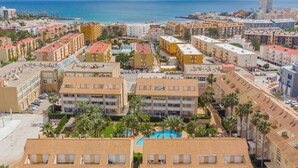 A coastal resort area with multiple hotel buildings, a swimming pool, and a beach in the background. - Syros Apartment (Javea / Xàbia)