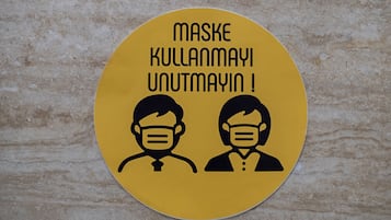 Un panneau circulaire jaune sur lequel figurent deux personnes portant des masques, et l’inscription : « N’oubliez pas de porter le masque ! »