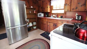 Una cucina compatta con mobili in legno, un frigorifero in acciaio inossidabile, un forno a microonde, un bollitore e un tostapane.