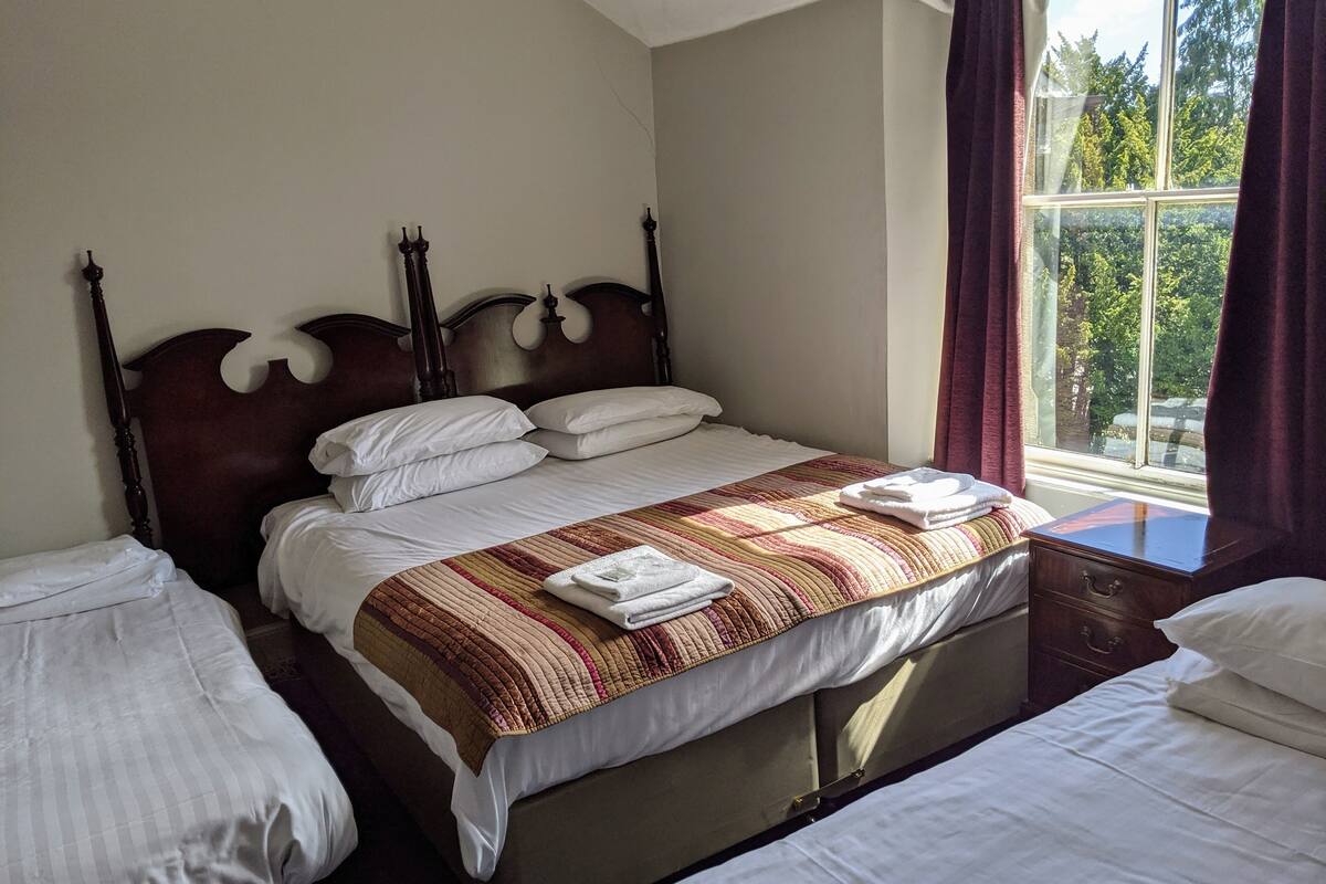 A hotel room with a large bed, two bedside tables, and a window with curtains.