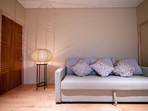 Une pièce avec un canapé gris, un lampadaire à motifs et une porte en bois.