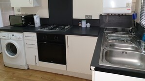 A compact kitchen with a washing machine, a microwave, a stove, and a sink. - Apartment in london 2 minute walk to metro, near Stratford 

 (London)