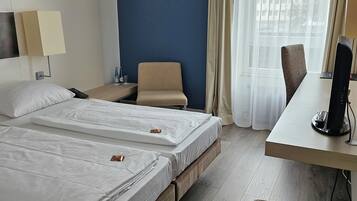 Une chambre d’hôtel avec deux lits, un bureau, une chaise et un téléviseur.