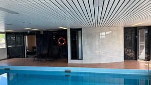 Ein moderner Innenpool mit klarer, blauer Wasseroberfläche, einem Rettungsring an der Wand und einem zeitgemäßen Deckenbau.