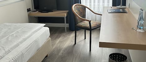 Une chambre d’hôtel avec un lit, un bureau, une chaise, une télévision et une lampe.