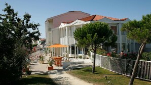 A hotel with a red-tiled roof, outdoor seating, and a white fence. - Apartment in France With Ocean View (Fouras)
